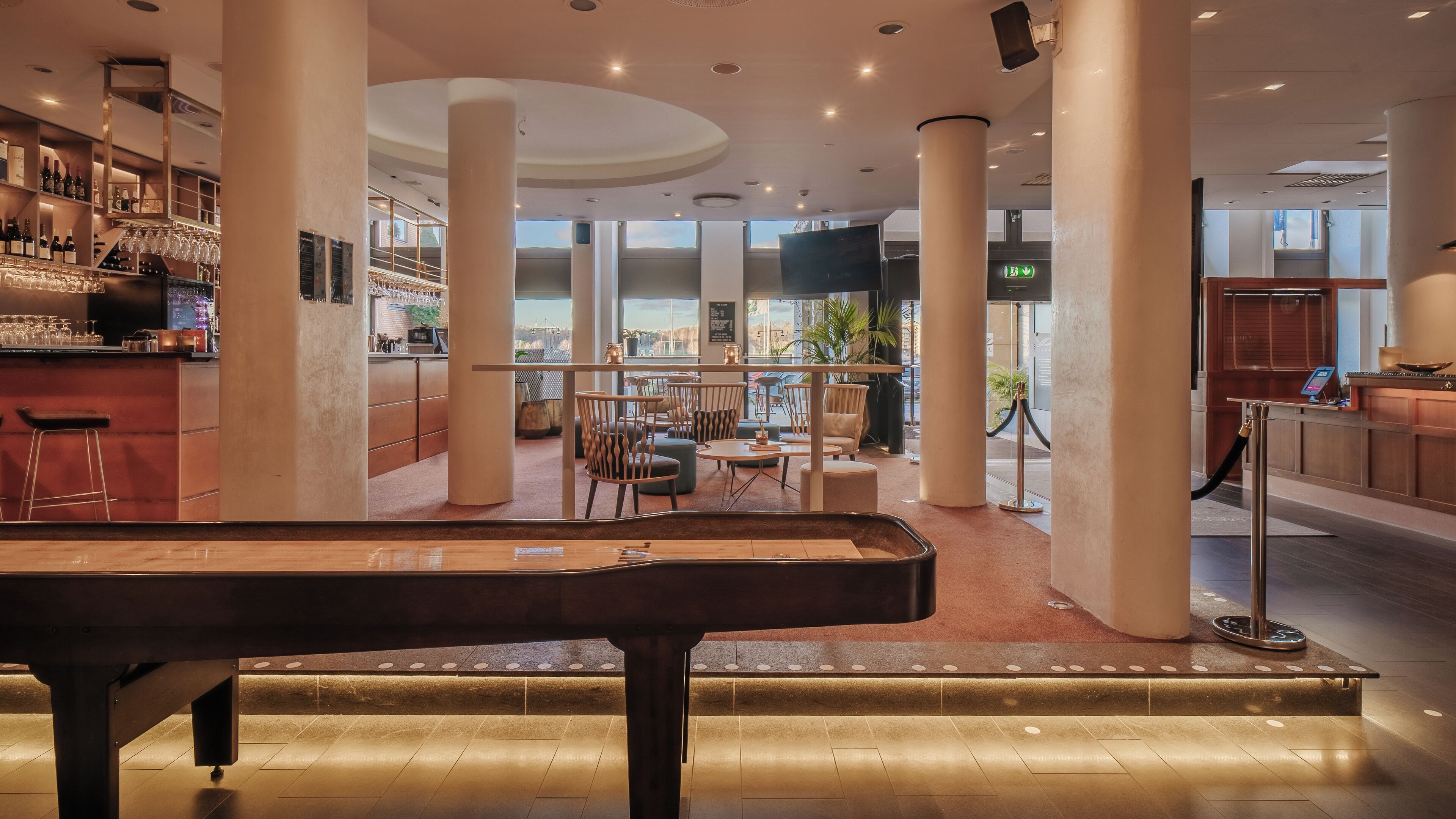 Um hall espaçoso com mesa de bilhar, assentos confortáveis, área de bar e grandes janelas com vista.