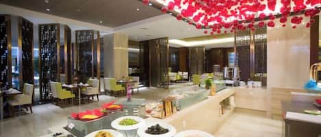 A hotel lobby with a buffet area, seating arrangements, and a decorative ceiling.