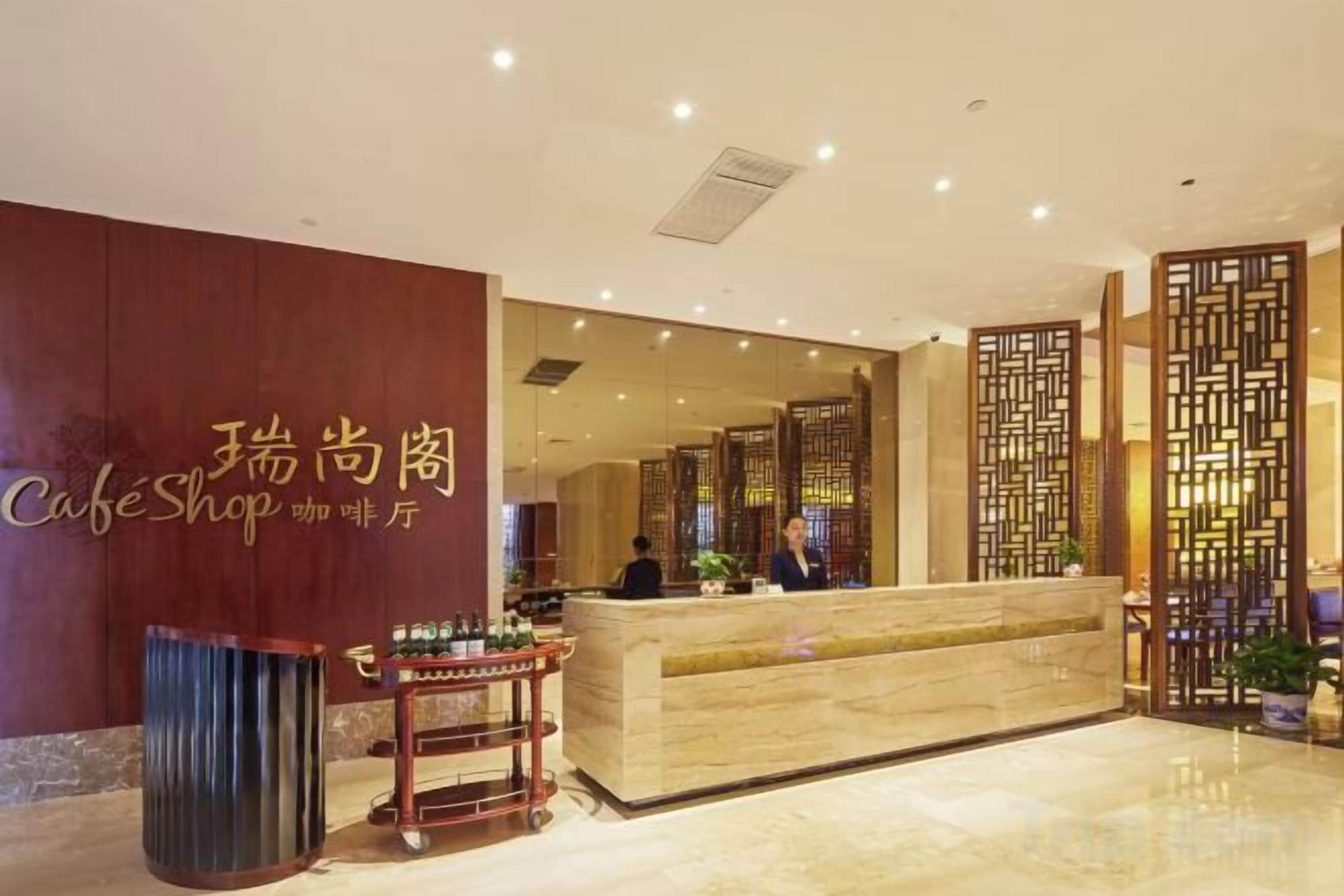A hotel reception area with a reception desk, a trash bin, and a decorative wall with a sign.
