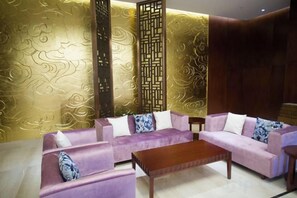 A room with a sofa set, a wooden coffee table, and a decorative screen. - Huaxi Hotel (Weihai)