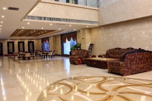Un hall d’entrée spacieux avec un plafond haut, un sol à motifs et des canapés en cuir.