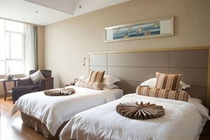 A hotel room with two beds, a large window, and a painting on the wall. - Huaxi Hotel (Weihai)