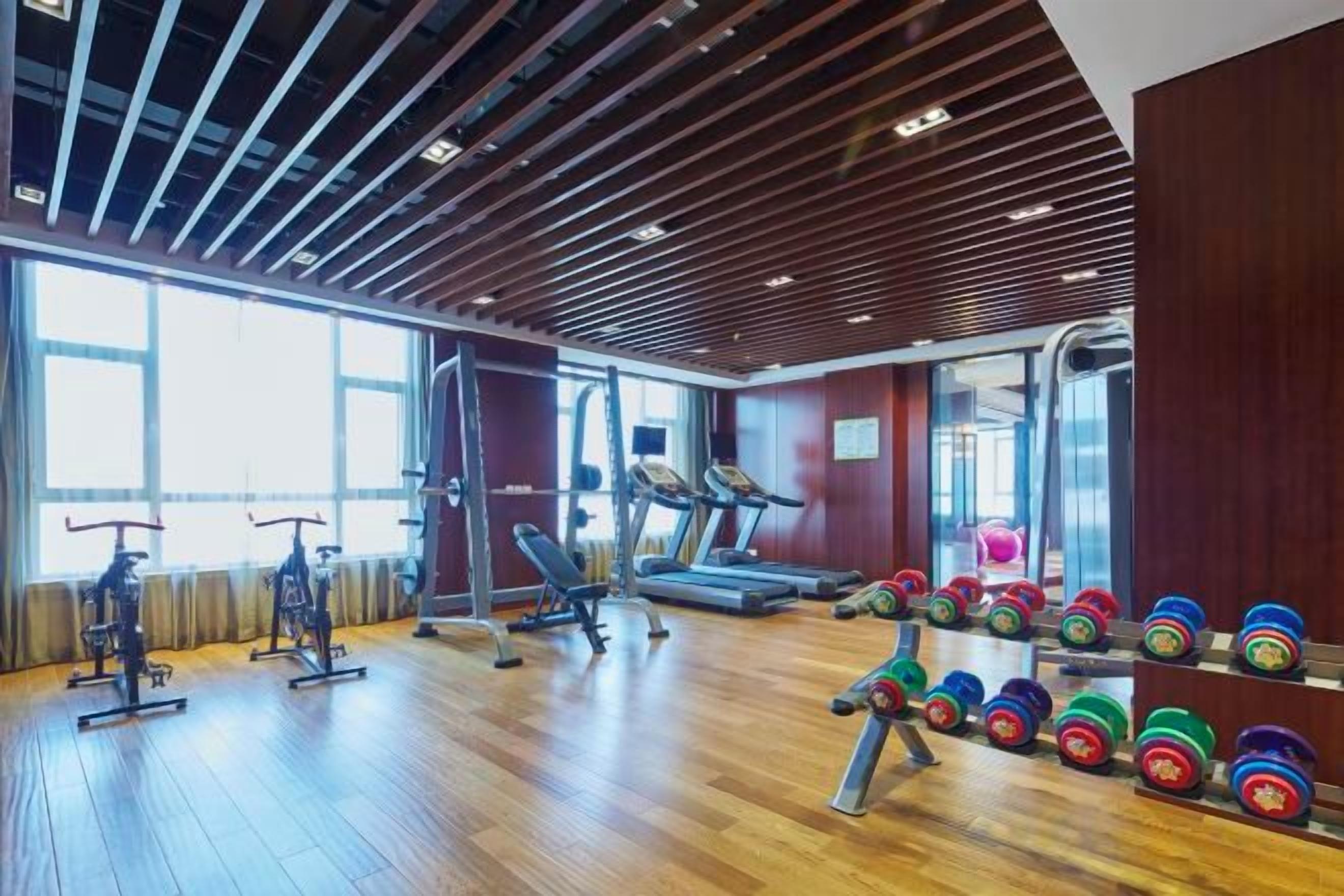 A gym with exercise equipment, a treadmill, and weightlifting stations.