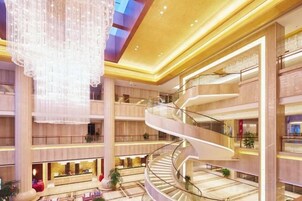 Un atrio de varios niveles con una escalera espiral central, grandes candelabros y múltiples pisos con locales comerciales.