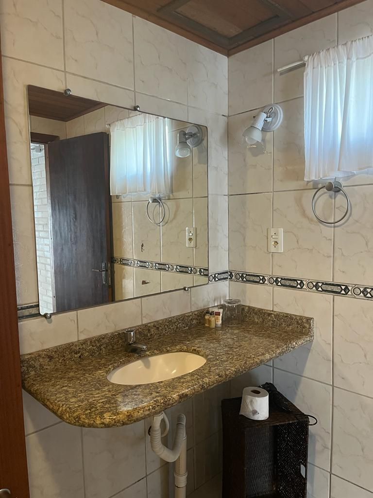 Une salle de bain avec un lavabo doté d’un plan de travail en granit, un miroir, un porte-serviettes et un porte-rouleau de papier toilette.