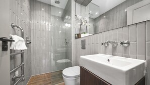 A modern bathroom with a large mirror, a white sink, and a glass shower enclosure.