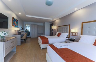 Habitación de hotel con dos camas, un escritorio, una silla, un espejo y un televisor.