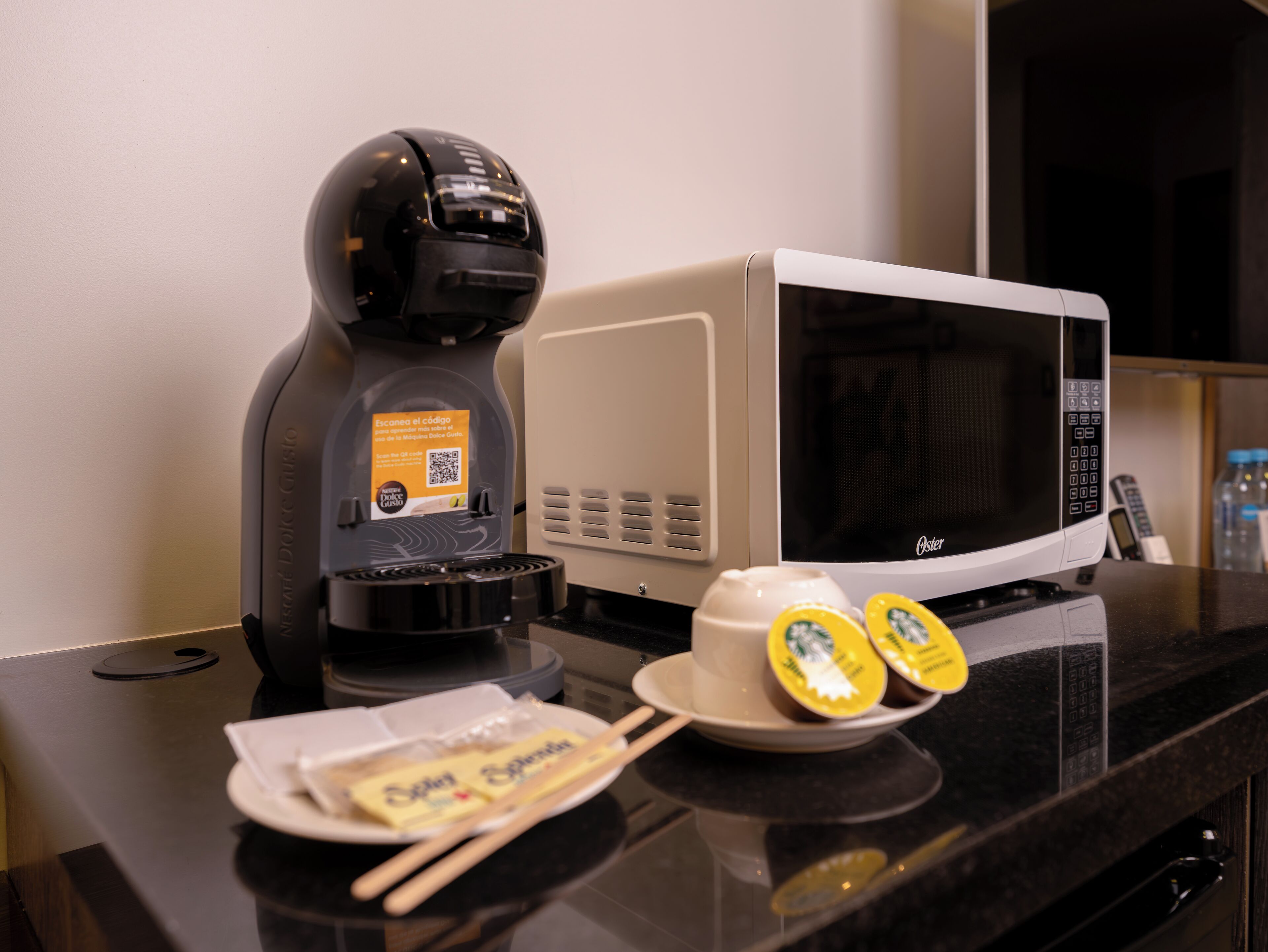 A kitchen area with a coffee maker, a microwave, and a plate with food items.