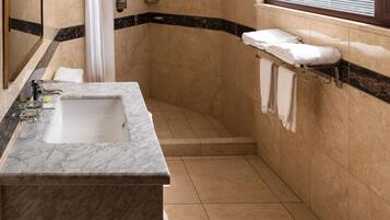 Un baño moderno con lavamanos de mármol, ducha y tocador con perchero.