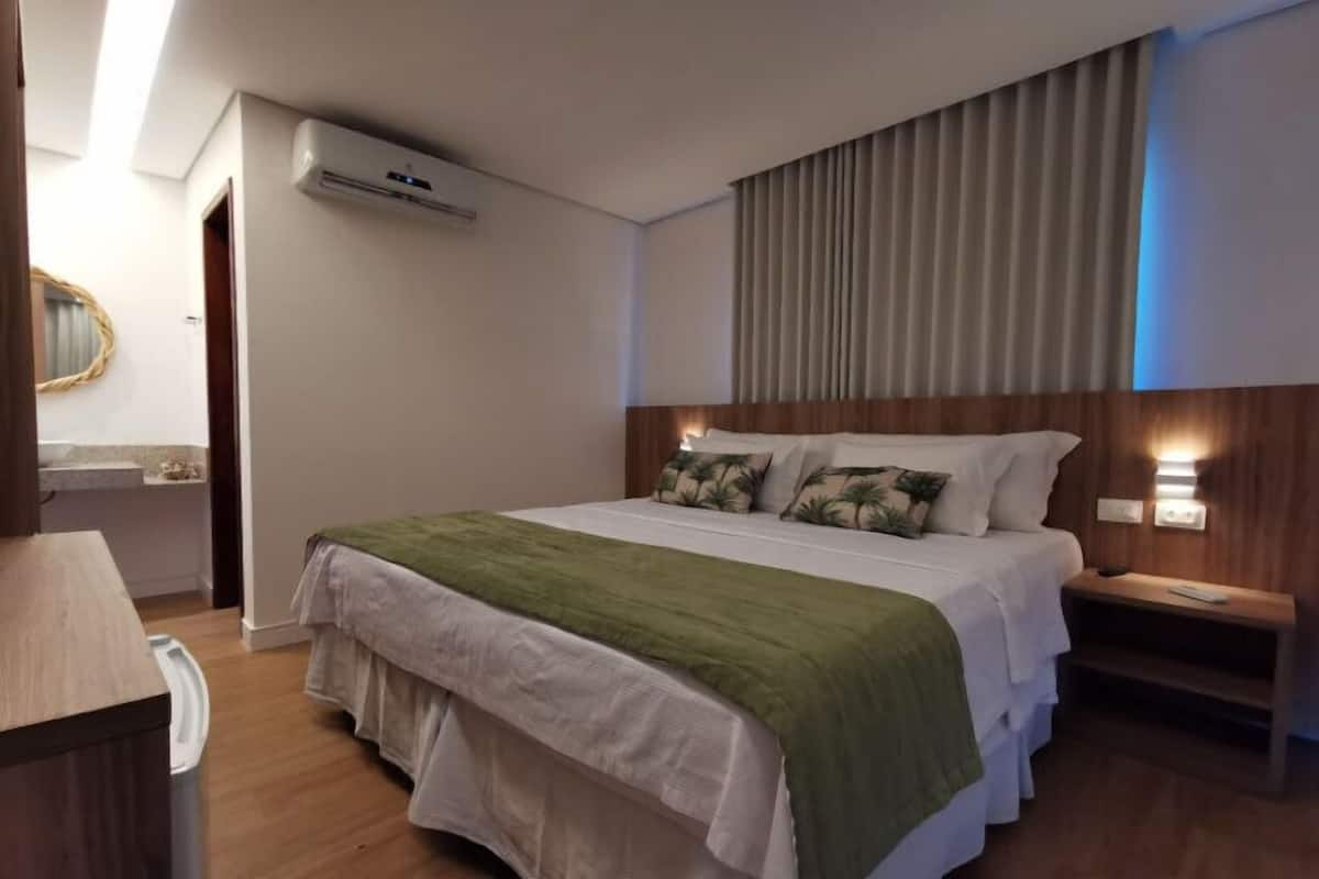 Ein Hotelzimmer mit Bett, Nachttisch und Klimaanlage.