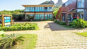 A modern building with a glass facade, a brick pathway leading to the entrance, and lush greenery surrounding the property. - Pousada Morro do Farol (Fernando de Noronha)