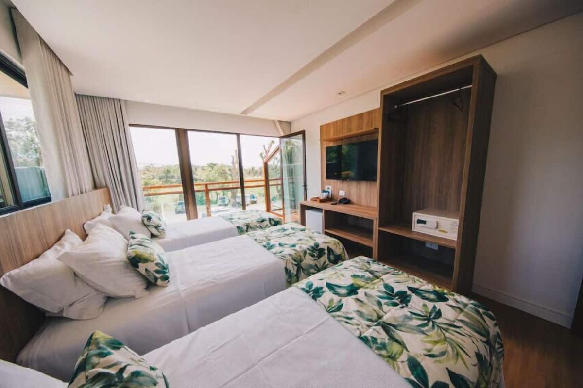 Ein Hotelzimmer mit zwei Betten, einem Fernseher, einem Schreibtisch und einem großen Fenster mit Blick.