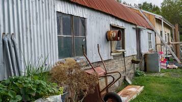 A corrugated metal building with a wooden door and a window.