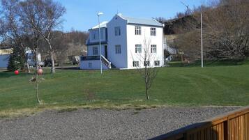 A white building with a blue roof, a staircase, and a small tree in the foreground.