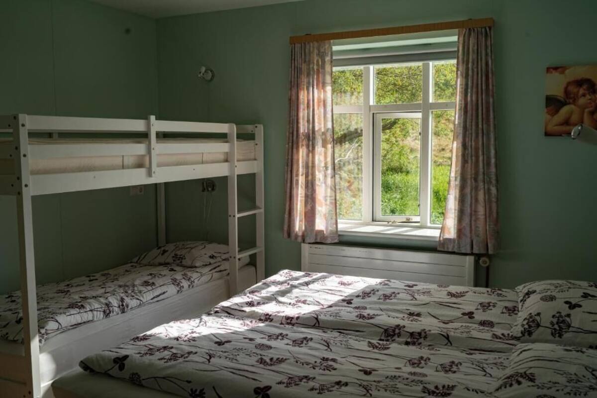 A room with bunk beds, a window with curtains, and a bed with floral bedding.