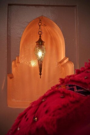 A wall-mounted lantern with a geometric pattern, hanging in front of a frosted glass window with a wooden frame. - Riad Sardinas & Chili (Marrakech)
