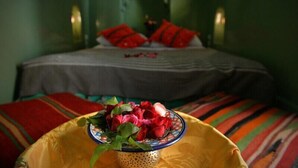 Una cama con almohadillas rojas y un cuenco de flores en primer plano.