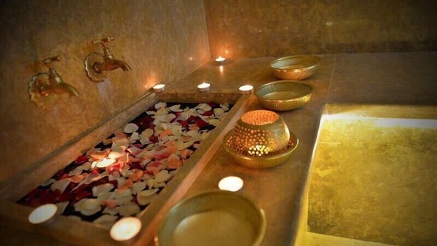 Un espacio de spa con bañera, velas y cuencos decorativos.