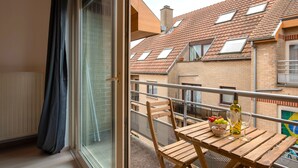 A balcony with a wooden table, chairs, and a bowl of fruit. - Jette Duplex Expo (Brussels)