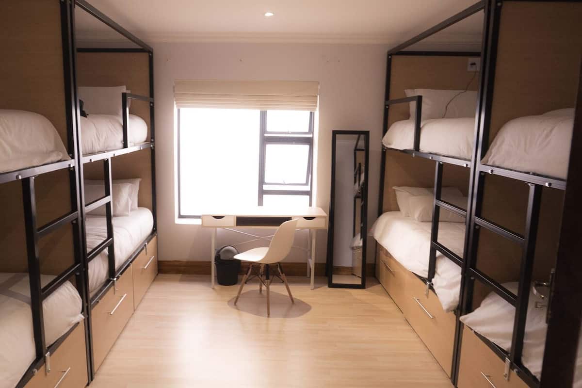 Une chambre de dortoir avec des lits superposés, un bureau et une fenêtre.