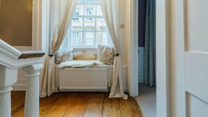 Ein Zimmer mit Fensterbank, weißen Vorhängen und Heizkörper.