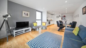 Un salon moderne avec un téléviseur à écran plat, un trépied et un canapé.