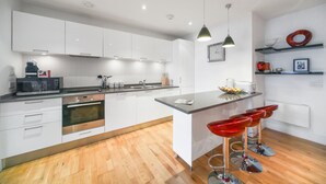 Une cuisine moderne avec des meubles blancs, un îlot central, un four à micro-ondes et un évier.