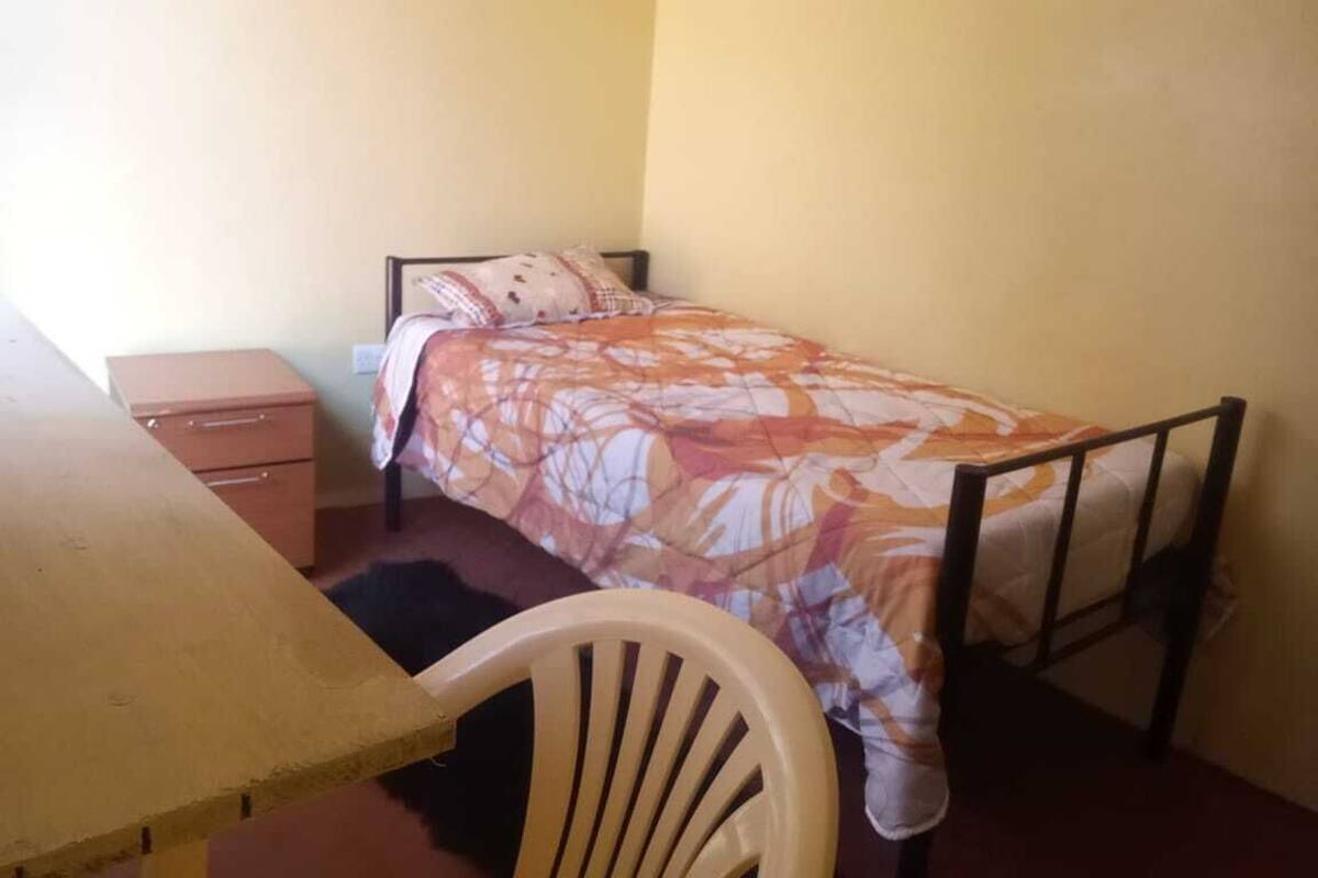 Habitación individual básica | Escritorio, tabla de planchar con plancha y ropa de cama