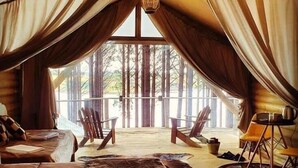 A cozy room with a large bed, a seating area with chairs, and a dining table.