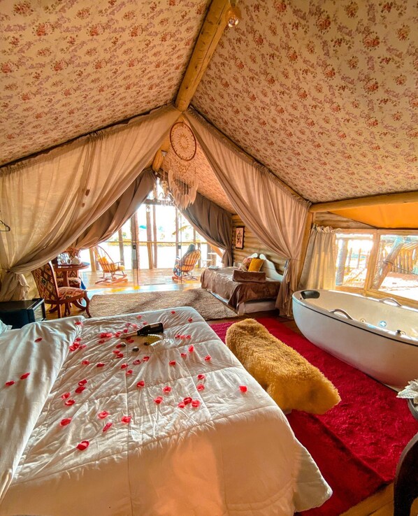 A cozy tented room with a bed, a red rug, a boat-shaped bathtub, and a wooden ceiling. - Tedesco Eco Park (São Francisco de Paula)