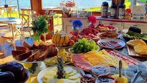 A buffet table with a variety of foods and beverages, set against a scenic lake view.