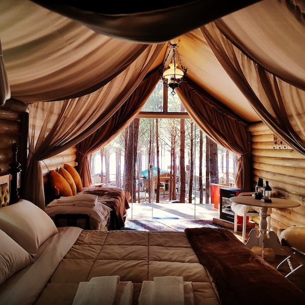 Een gezellige slaapkamer met een groot bed, een klein tafeltje en uitzicht op het bos.