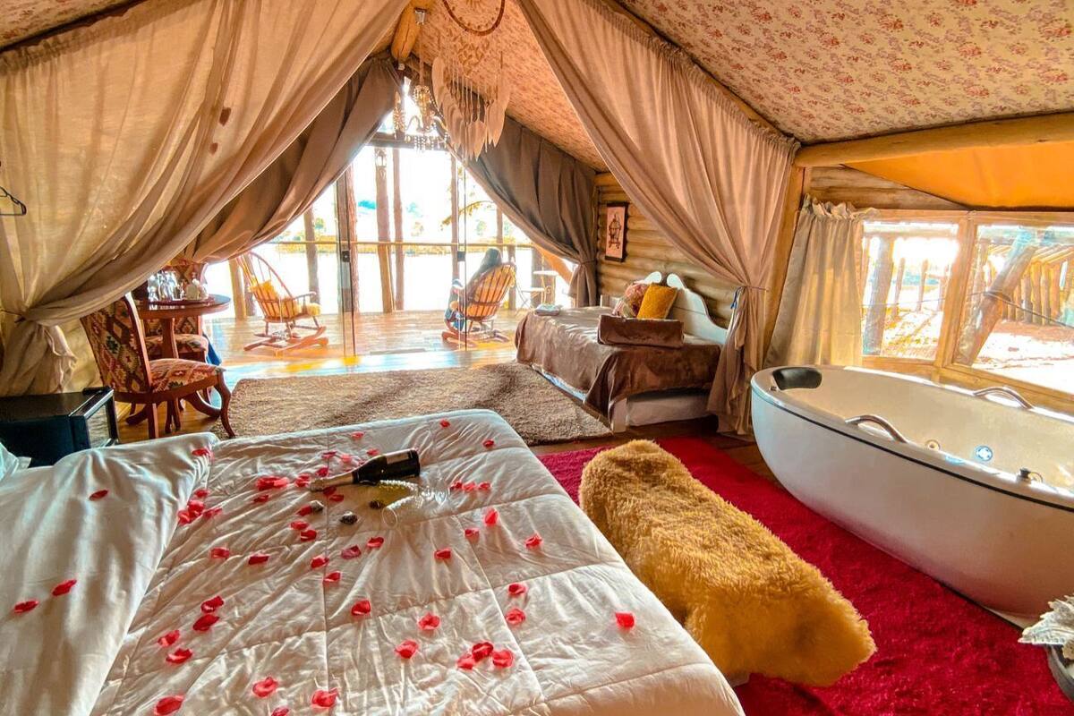 Un hébergement sous tente comprenant un lit, un tapis rouge, un bateau et une chaise.