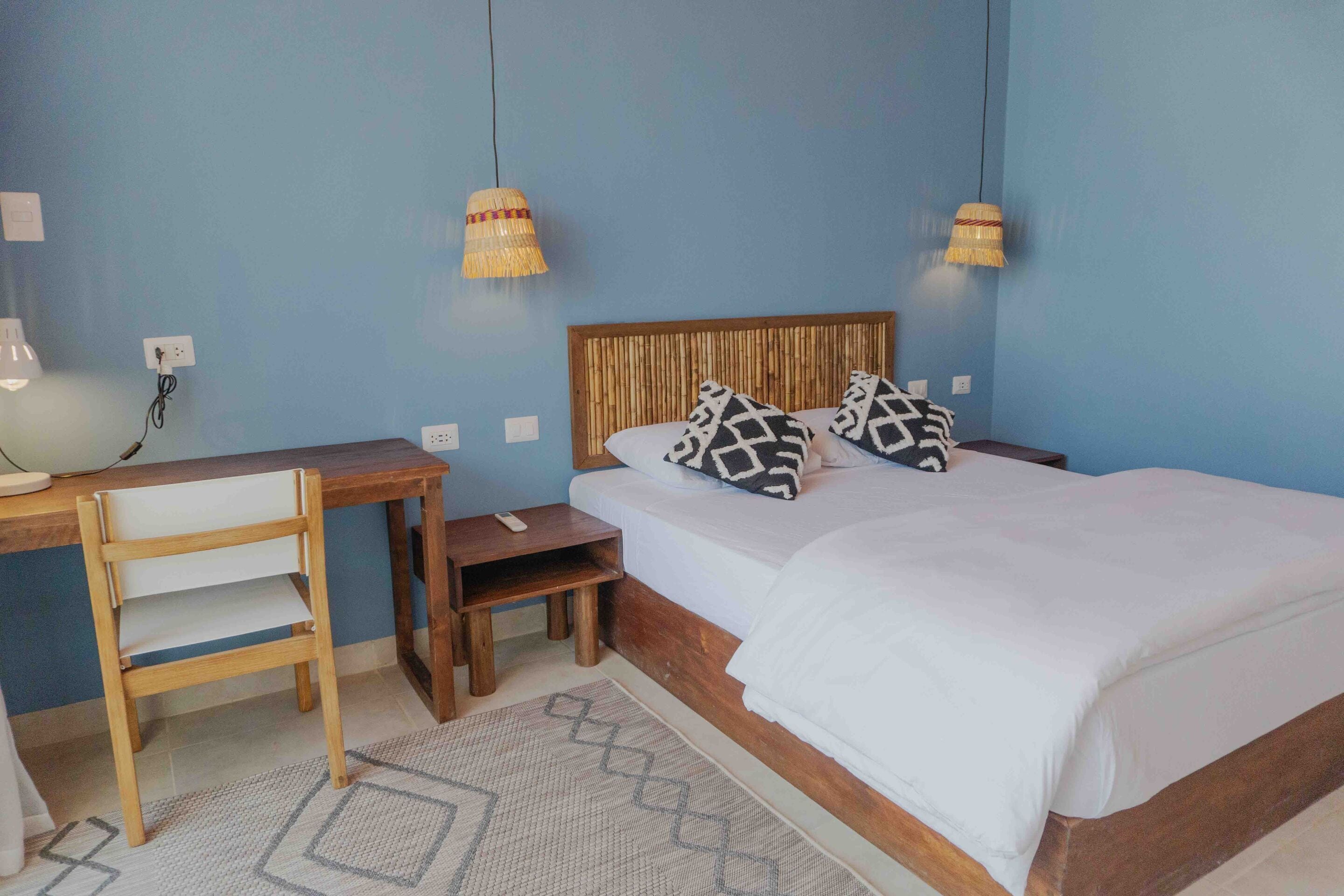 A bedroom with a wooden bed, two nightstands, a desk, and a chair.