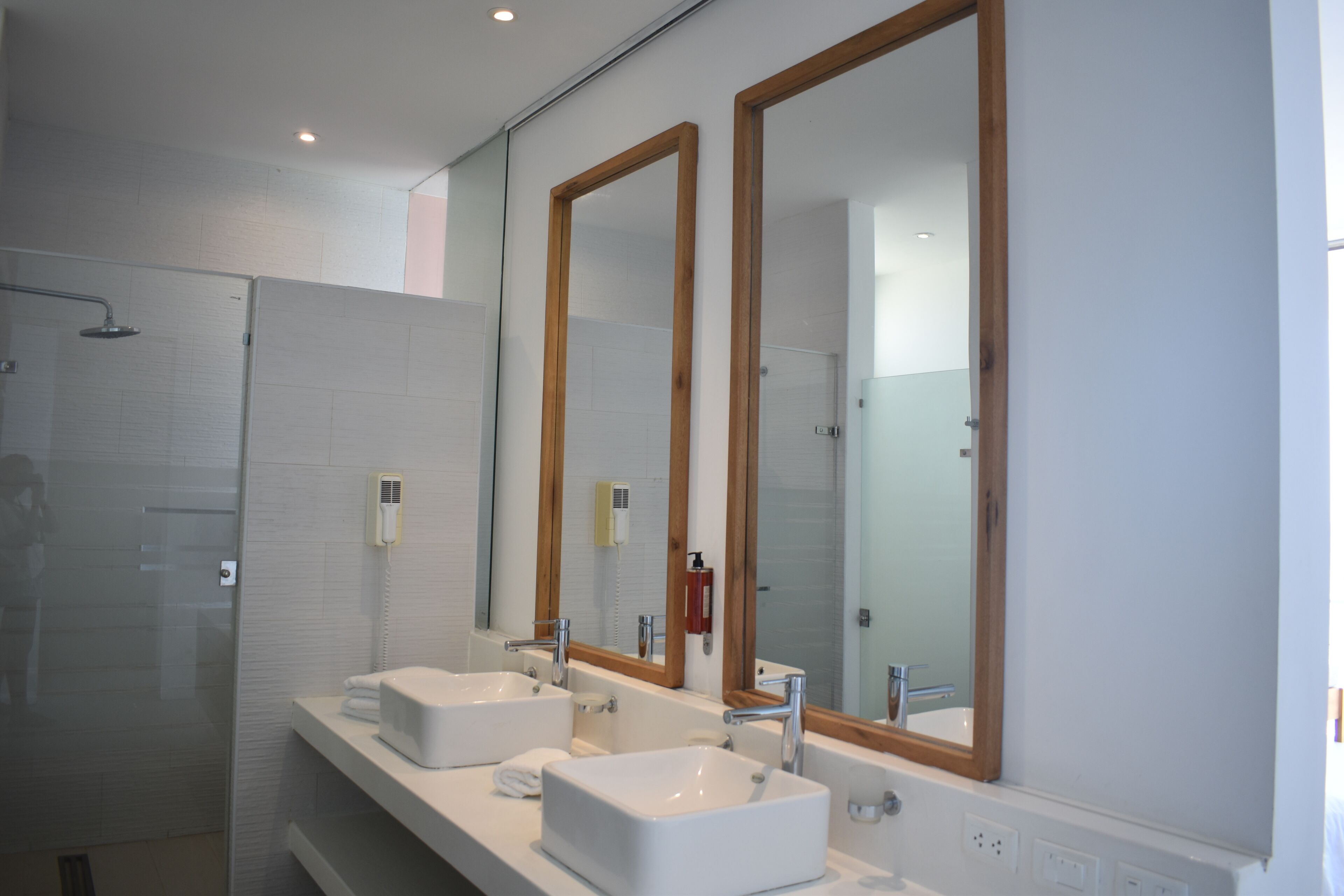 A modern bathroom with two sinks, a glass shower enclosure, and large mirrors.