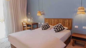 Cama bem arrumada com cabeceira de madeira, duas almofadas estampadas e mesa de cabeceira com abajur.