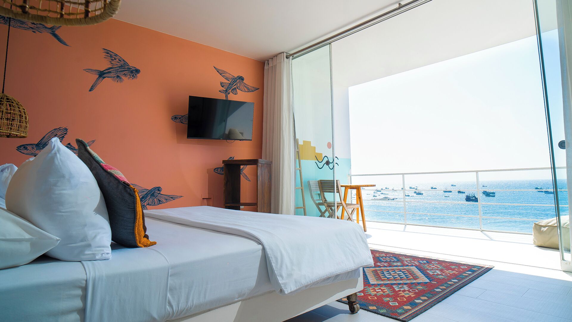 Ein Schlafzimmer mit Bett, Fernseher, einem Fenster mit Meerblick und einem Balkon.