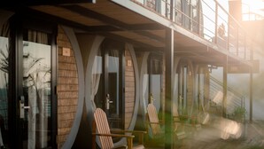 A modern hotel with a wooden exterior, large windows, and a balcony with chairs. - qema Mancora (Máncora)