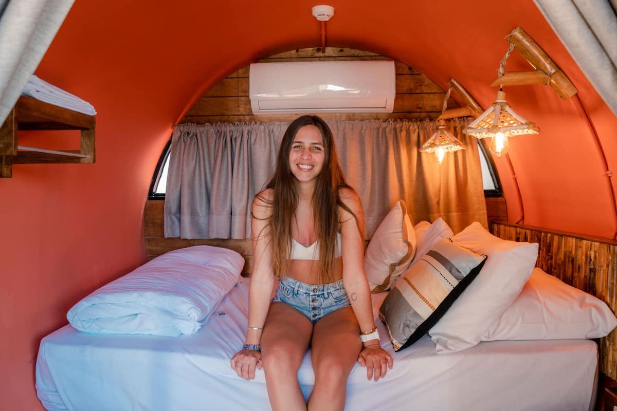 A cozy, enclosed sleeping area with a bed, curtains, and a hanging light fixture.