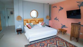 Een slaapkamer met een bed, een ronde spiegel erboven, een televisie aan de muur en een kamerkleed met dessin.