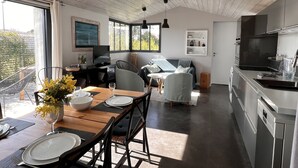 A modern kitchen with a dining area, a sofa, and a TV. - Maison d'Hotes les Petites Terres (Sainte-Marie-de-Re)