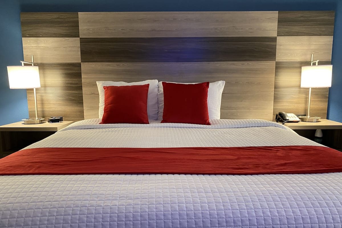 Een hotelkamer met een groot bed, twee bedlampjes, een telefoon en een houten hoofdeinde.