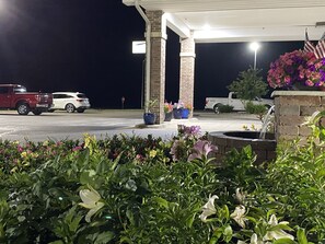 A gas station at night with a covered parking area, a brick pillar, and potted plants. - Garnett Hotel & RV Park (Garnett)