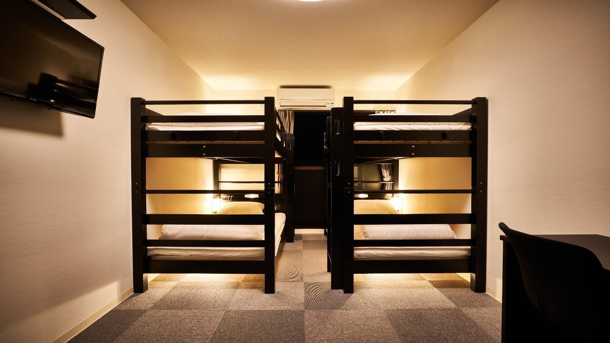 A narrow hallway with two bunk beds, a flat-screen TV mounted on the wall, and a ceiling-mounted air conditioning unit.