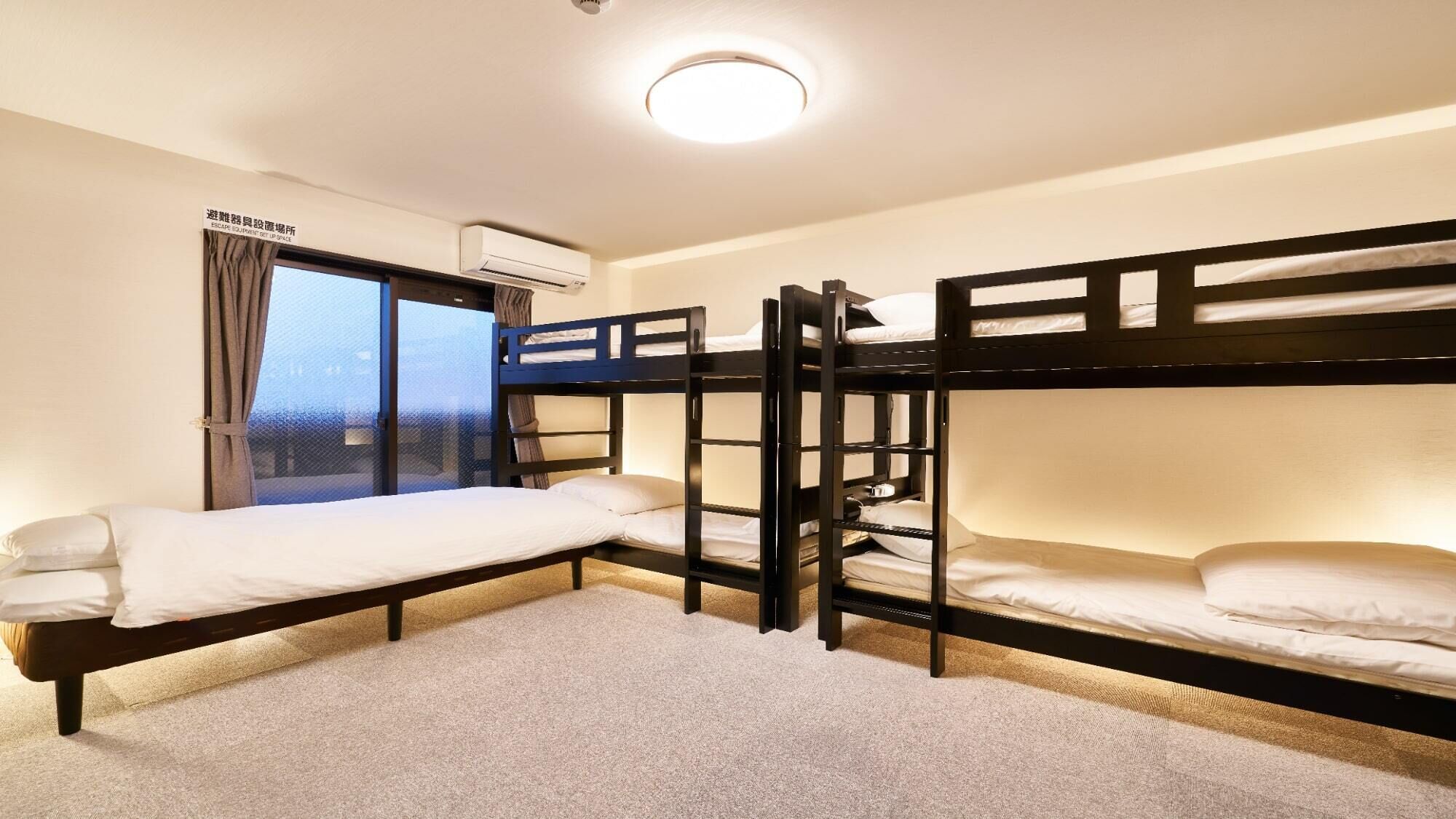 A bunk room with three bunk beds, a window with curtains, an air conditioning unit, and a carpeted floor.