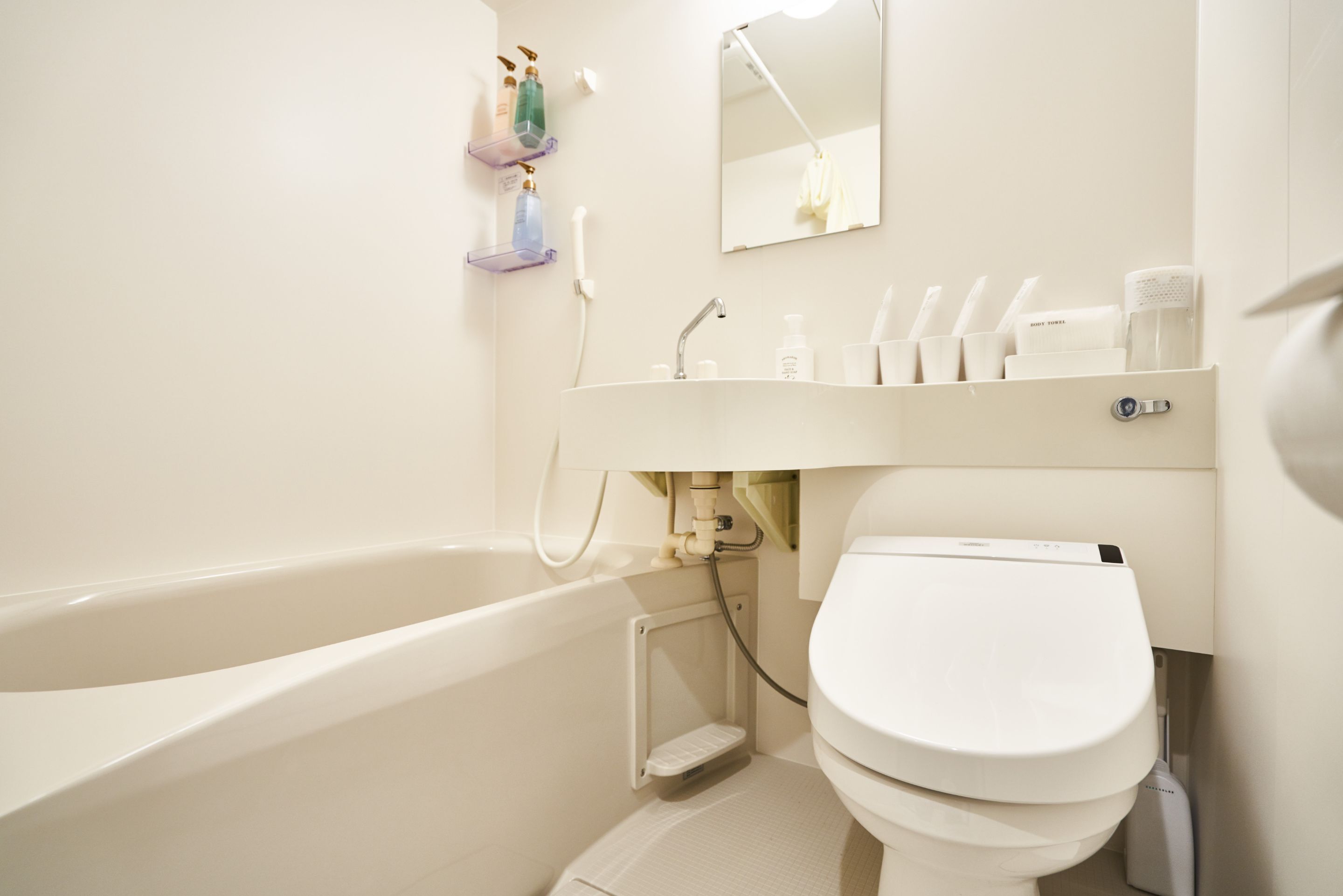 A bathroom with a bathtub, toilet, and a sink area with toiletries.