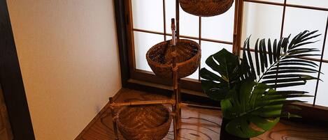 A room with a wooden floor, a bamboo shelf with baskets, and a potted plant.