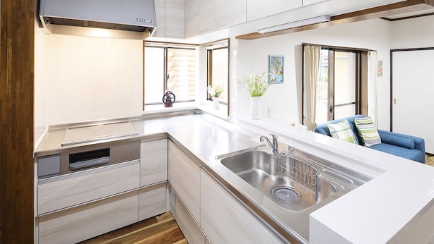 Una cocina compacta con lavaplatos integrado, suelo de madera y un sofá azul en la zona de estar contigua.
