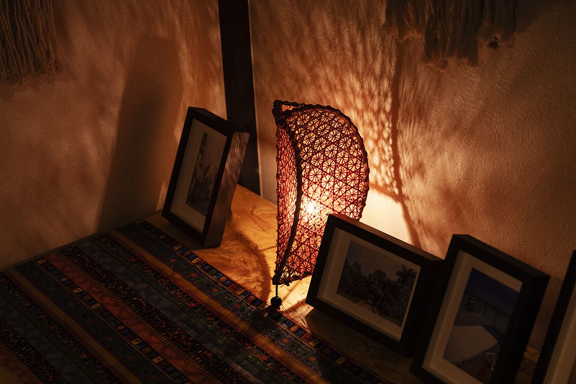 A room with a patterned rug, a decorative hanging light fixture, and framed pictures on the wall.
