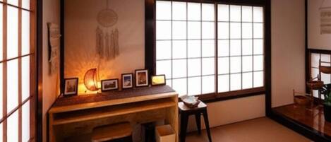 Een traditionele Japanse kamer met tatami vloerbedekking, een laag houten bureau en een shoji schuifdeur.